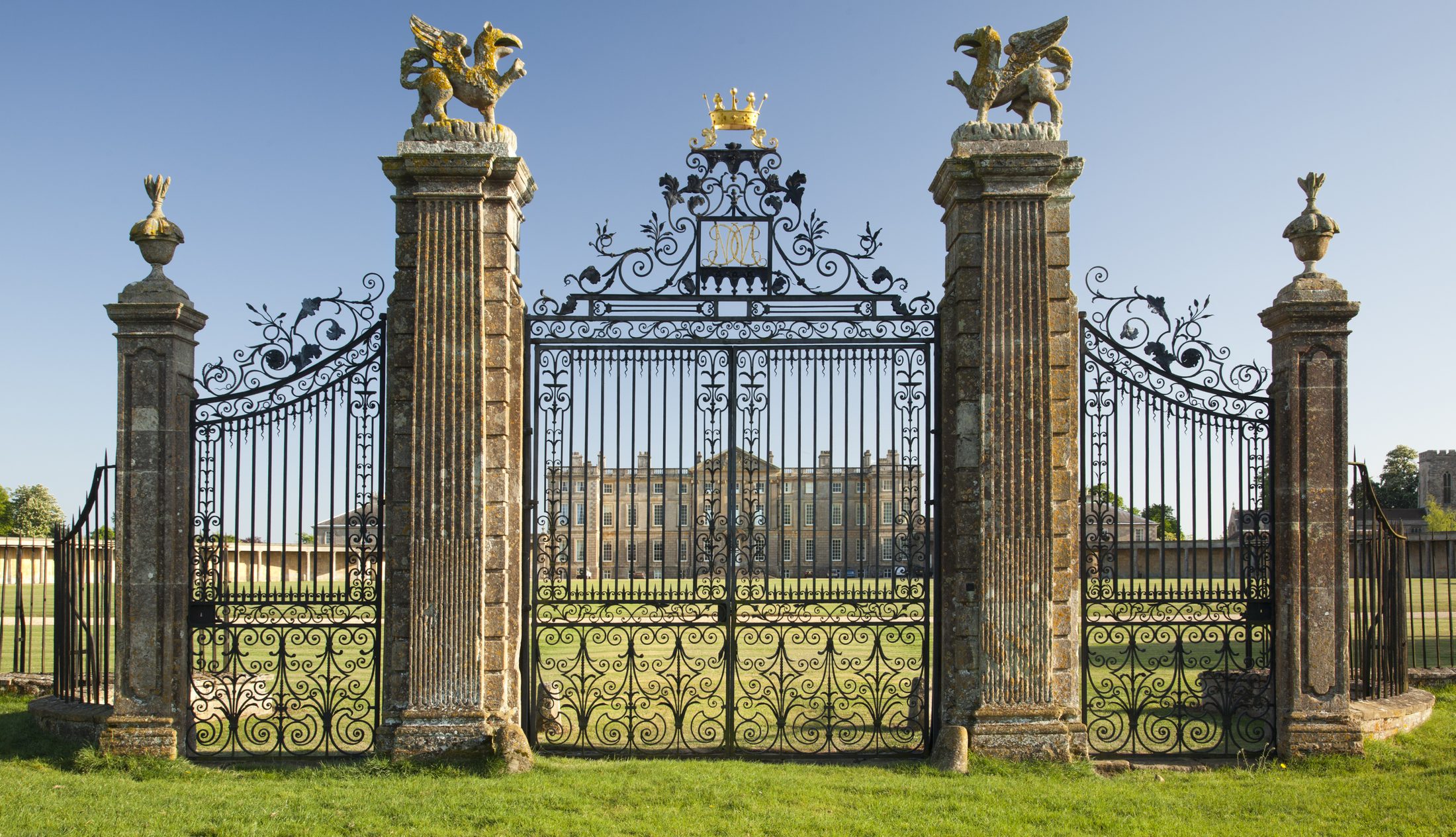 The wrought-iron entrance gates, with gilded finials, seen from the drive