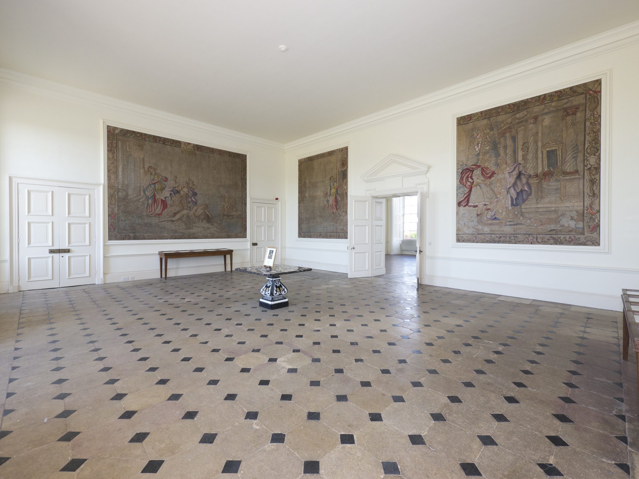 The Tapestry Hall, with large tapestries on the walls and a stone chequerboard floor