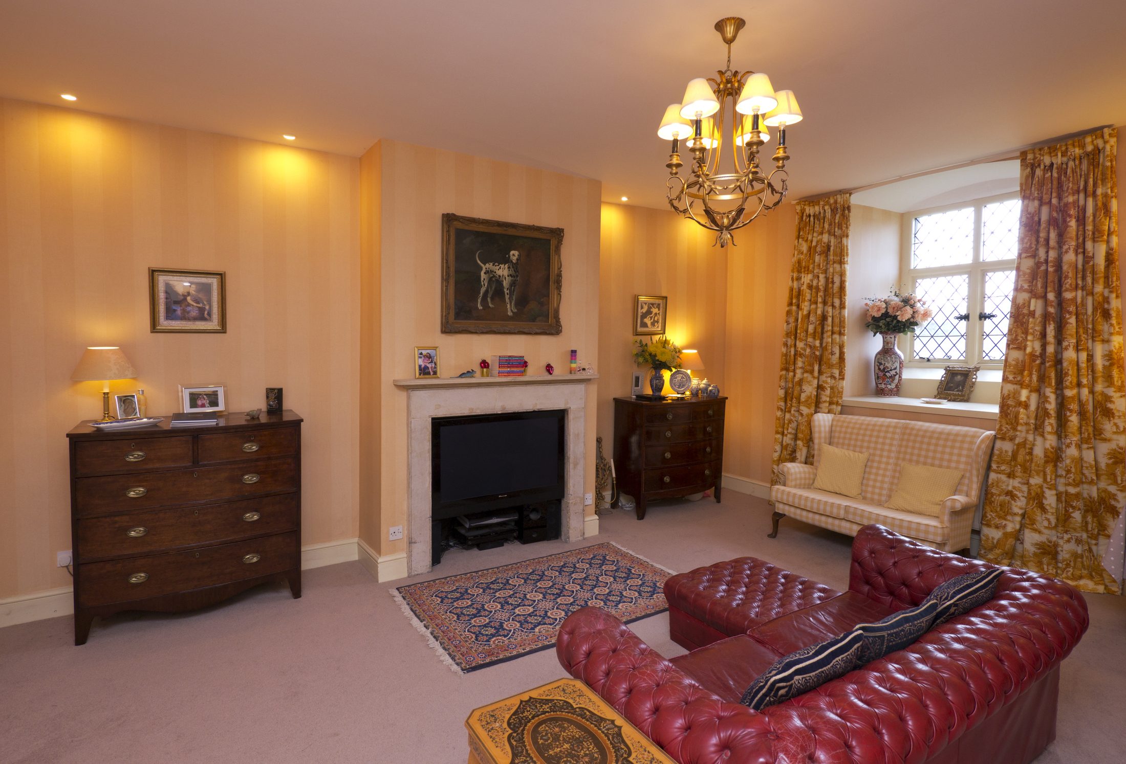 The Sitting Room, with a red leather sofa and fireplace