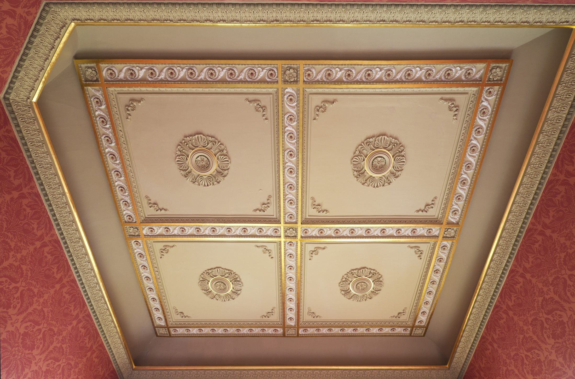 A coffered ceiling picked out in red and gold, above the Dining Room